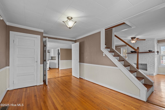 209 N 8th St, Morehead City, NC 28557 - stairs featuring hardwood / wood-style flooring, a wainscoted wall, ornamental molding, a ceiling fan, and a fireplace