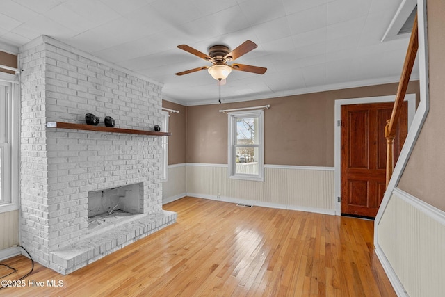 209 N 8th St, Morehead City, NC 28557 - unfurnished living room with hardwood / wood-style flooring, ceiling fan, a wainscoted wall, a brick fireplace, and ornamental molding