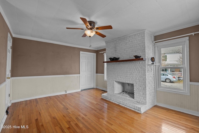 209 N 8th St, Morehead City, NC 28557 - unfurnished living room with hardwood / wood-style flooring, ceiling fan, a brick fireplace, wainscoting, and crown molding