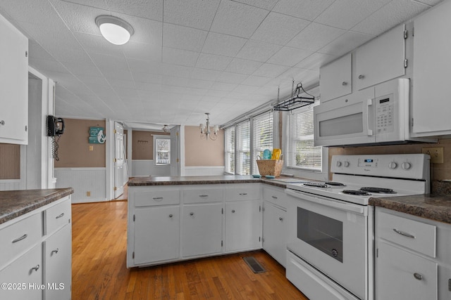 209 N 8th St, Morehead City, NC 28557 - kitchen with white appliances, dark countertops, wood finished floors, wainscoting, and a peninsula