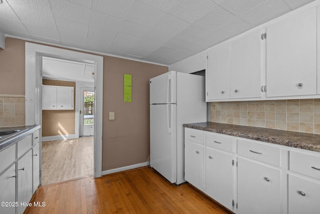209 N 8th St, Morehead City, NC 28557 - kitchen featuring freestanding refrigerator, light wood-style floors, decorative backsplash, white cabinetry, and dark countertops