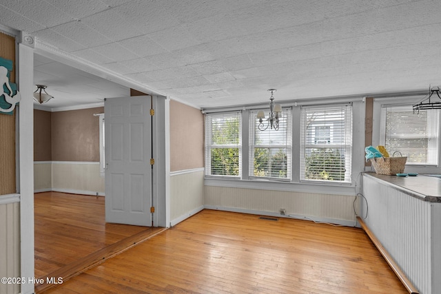 209 N 8th St, Morehead City, NC 28557 - unfurnished dining area with a chandelier, light wood-style flooring, a wainscoted wall, and ornamental molding