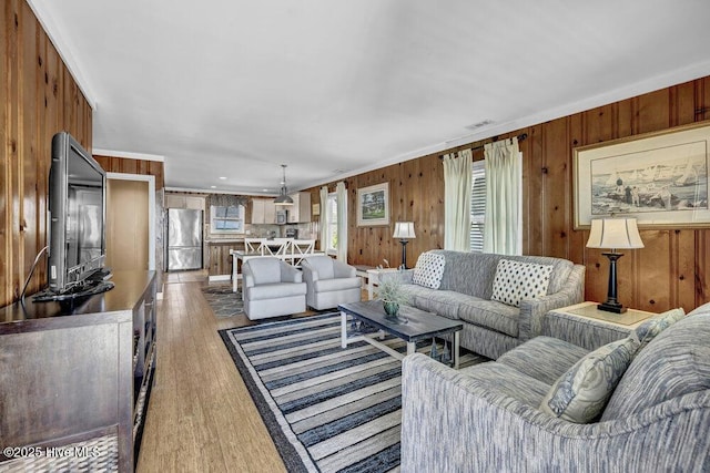 living room featuring wood finished floors, visible vents, and wood walls