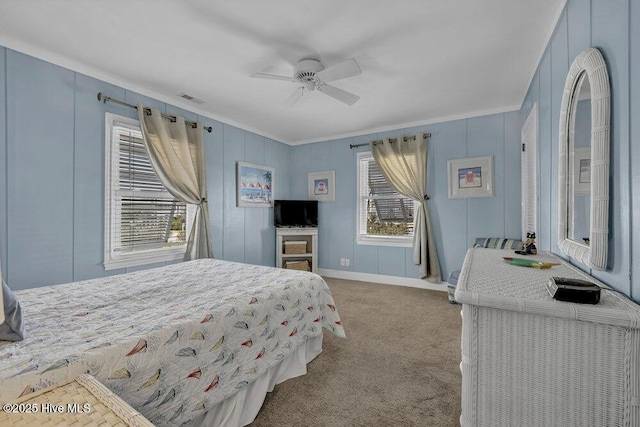 carpeted bedroom featuring visible vents, baseboards, ornamental molding, and a ceiling fan