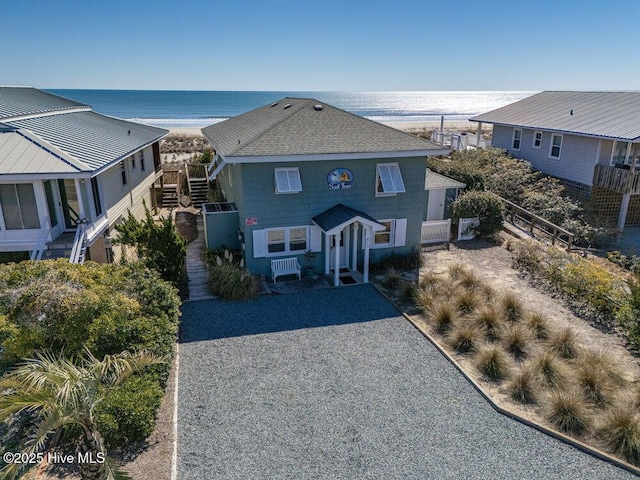 view of front of house featuring stairway, a water view, and a shingled roof