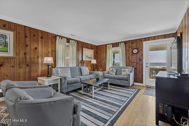 living room with light wood finished floors, visible vents, and wood walls