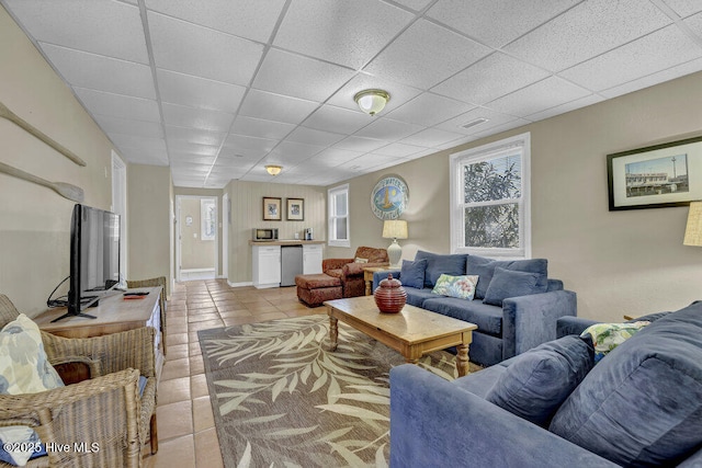 living room featuring tile patterned floors and a drop ceiling