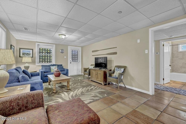 tiled living area with a drop ceiling, baseboards, and visible vents