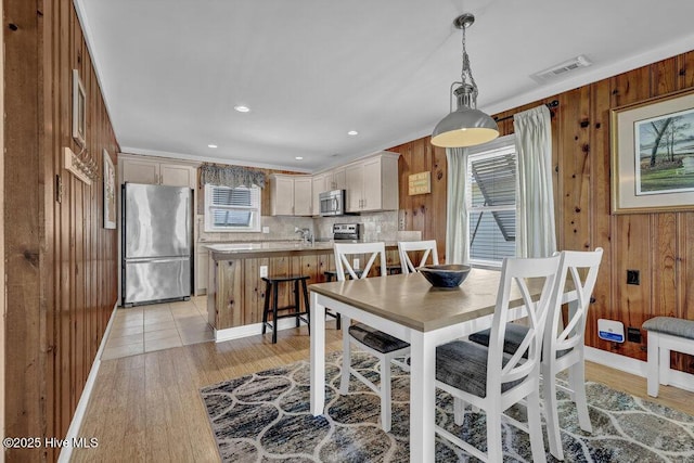 dining room with light wood-style floors, visible vents, wooden walls, and recessed lighting