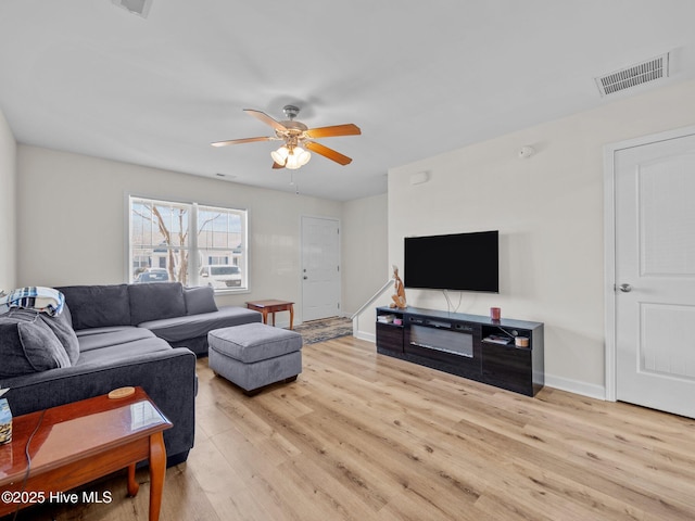 living area featuring a ceiling fan, wood finished floors, visible vents, and baseboards