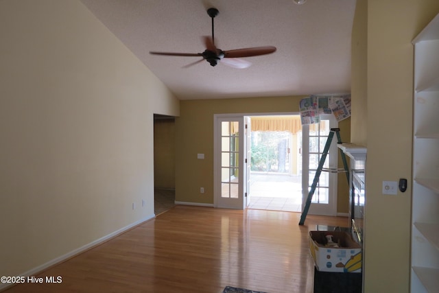 interior space featuring ceiling fan, baseboards, lofted ceiling, and wood finished floors