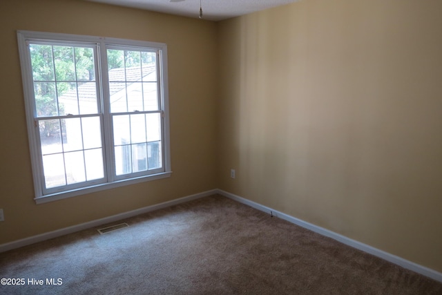 carpeted spare room with baseboards, visible vents, and ceiling fan