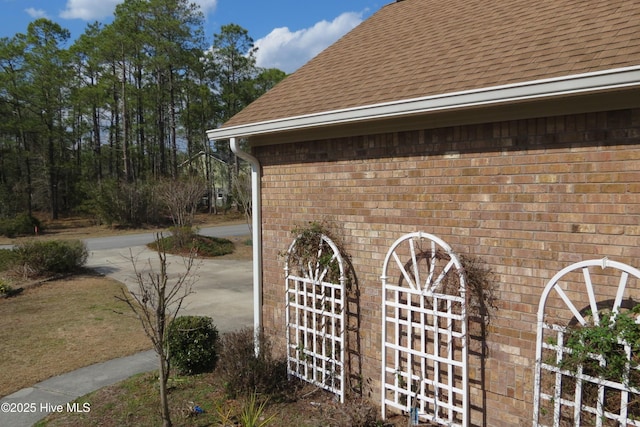 view of side of property with brick siding and a shingled roof