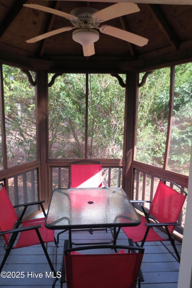 wooden deck with outdoor dining area and ceiling fan