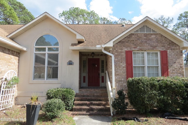 view of front of property with brick siding, stucco siding, and a shingled roof