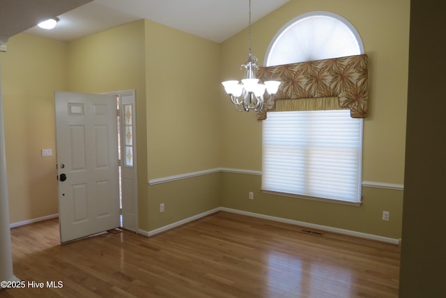 foyer entrance featuring visible vents, an inviting chandelier, wood finished floors, and a healthy amount of sunlight