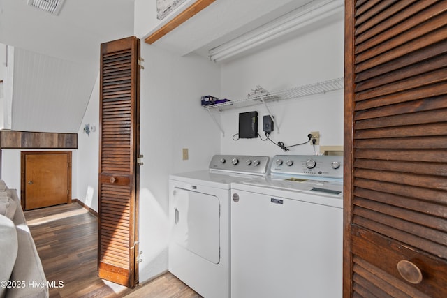 laundry room with light wood-style floors, separate washer and dryer, visible vents, and laundry area