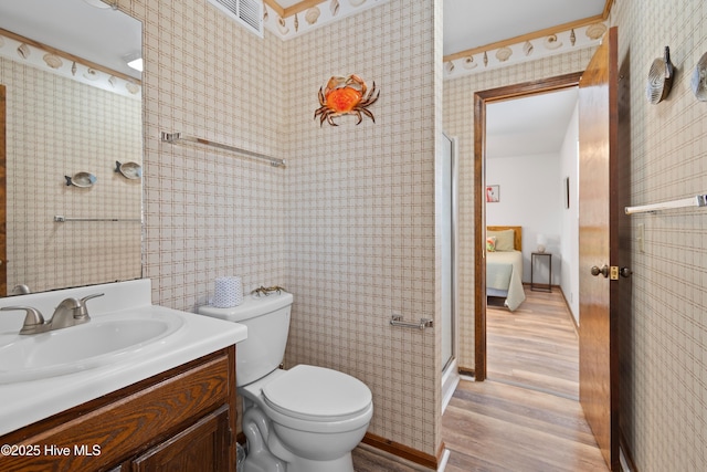 full bathroom featuring wallpapered walls, toilet, a stall shower, wood finished floors, and vanity