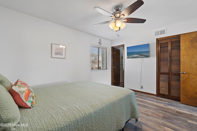 bedroom with visible vents, a ceiling fan, wood finished floors, a closet, and baseboards