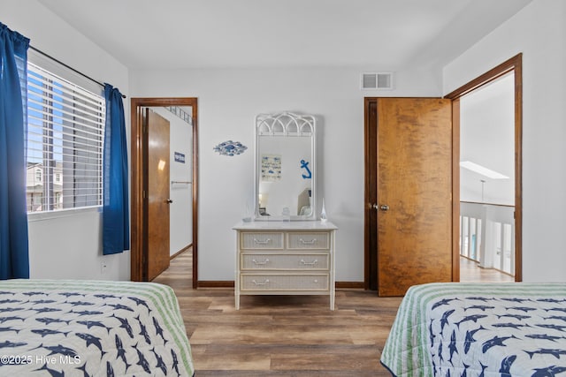 bedroom featuring wood finished floors, visible vents, and baseboards