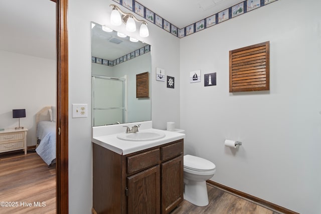 bathroom featuring vanity, wood finished floors, baseboards, a stall shower, and toilet