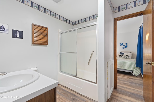 full bathroom featuring connected bathroom, wood finished floors, bath / shower combo with glass door, and a sink