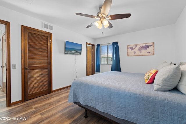 bedroom featuring visible vents, a ceiling fan, baseboards, and wood finished floors