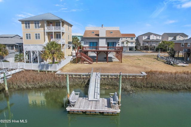 view of dock featuring stairway, fence, a water view, and a residential view