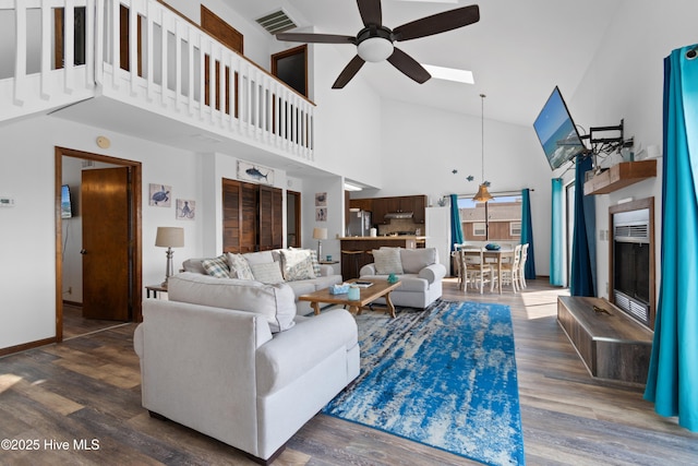 living area with visible vents, a skylight, a ceiling fan, and wood finished floors