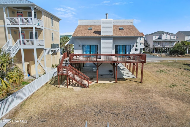 rear view of house featuring a lawn, a fenced backyard, stairs, roof with shingles, and a chimney