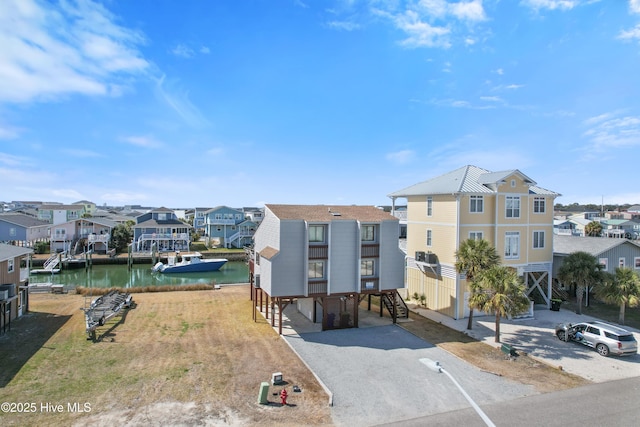 view of building exterior with a residential view, a carport, driveway, and a water view