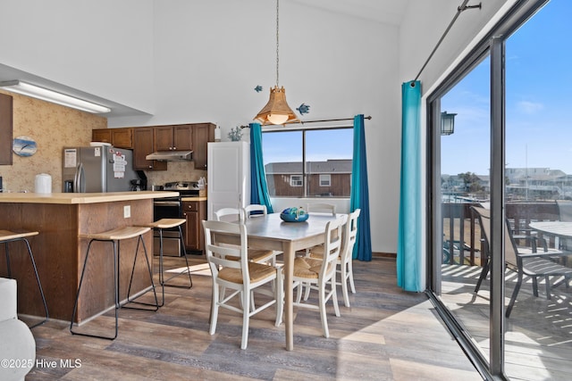 dining area featuring a high ceiling and light wood-style flooring