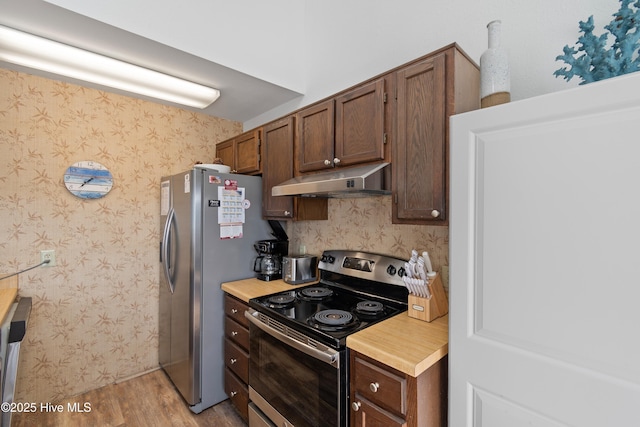 kitchen featuring wallpapered walls, light countertops, light wood-style floors, under cabinet range hood, and appliances with stainless steel finishes