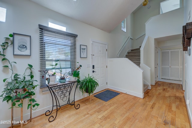 entrance foyer with a wealth of natural light, stairway, baseboards, and wood finished floors