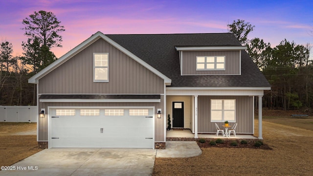 view of front facade with fence, roof with shingles, covered porch, concrete driveway, and a garage