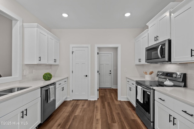 kitchen with a sink, appliances with stainless steel finishes, light countertops, and white cabinetry