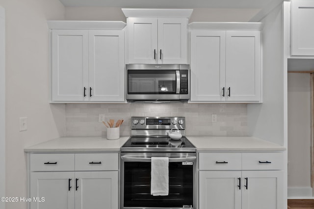 kitchen with backsplash, appliances with stainless steel finishes, white cabinetry, and light countertops