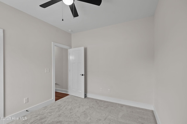 carpeted empty room with a ceiling fan and baseboards