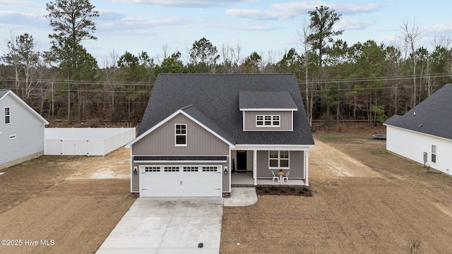 view of front of home featuring covered porch, an attached garage, concrete driveway, and a shingled roof