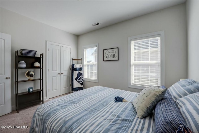 bedroom with a closet, visible vents, and carpet floors