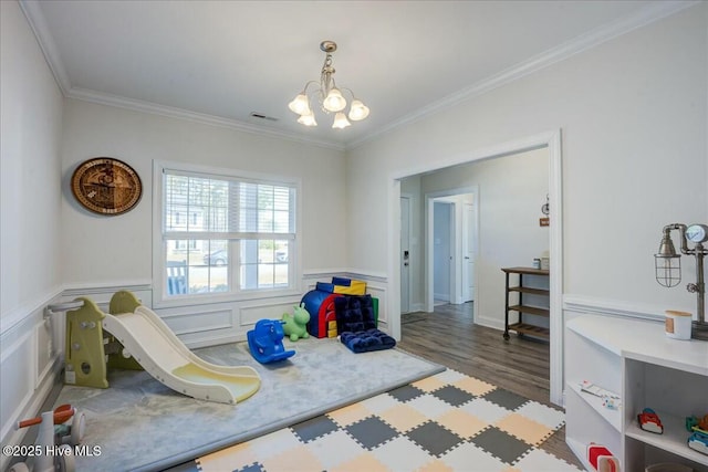 recreation room featuring visible vents, a notable chandelier, wood finished floors, and crown molding