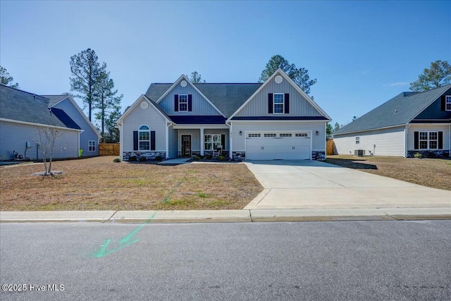 craftsman house with board and batten siding, a front lawn, cooling unit, stone siding, and driveway