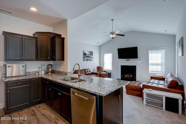 kitchen featuring light stone counters, visible vents, a peninsula, a sink, and stainless steel dishwasher