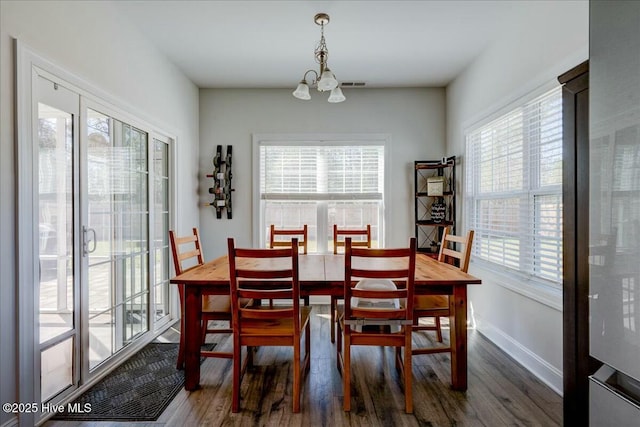 dining area featuring a notable chandelier, visible vents, baseboards, and wood finished floors