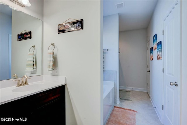 full bathroom with visible vents, a bathing tub, baseboards, and vanity