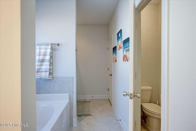 full bath with baseboards, tile patterned flooring, toilet, and a garden tub