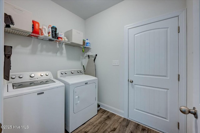 laundry room featuring washer and dryer, baseboards, wood finished floors, and laundry area