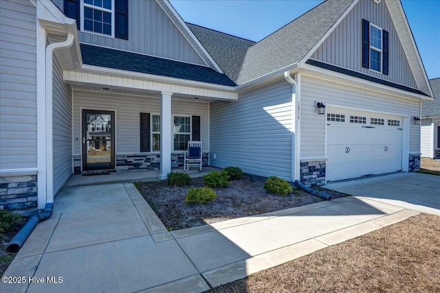 property entrance with board and batten siding, roof with shingles, covered porch, a garage, and stone siding