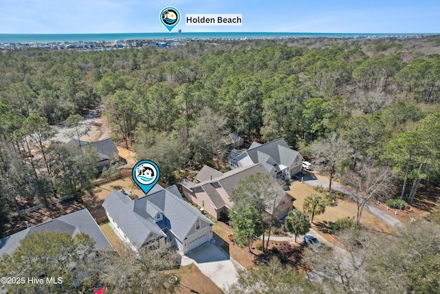 birds eye view of property featuring a forest view and a water view