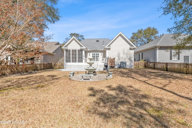 rear view of property with a yard, a fenced backyard, and a sunroom